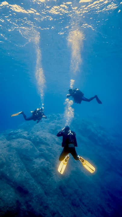 Foto Diving Chia: Tre amici, una stessa onda di bolle. Si scende a uno, ma si sale insieme.